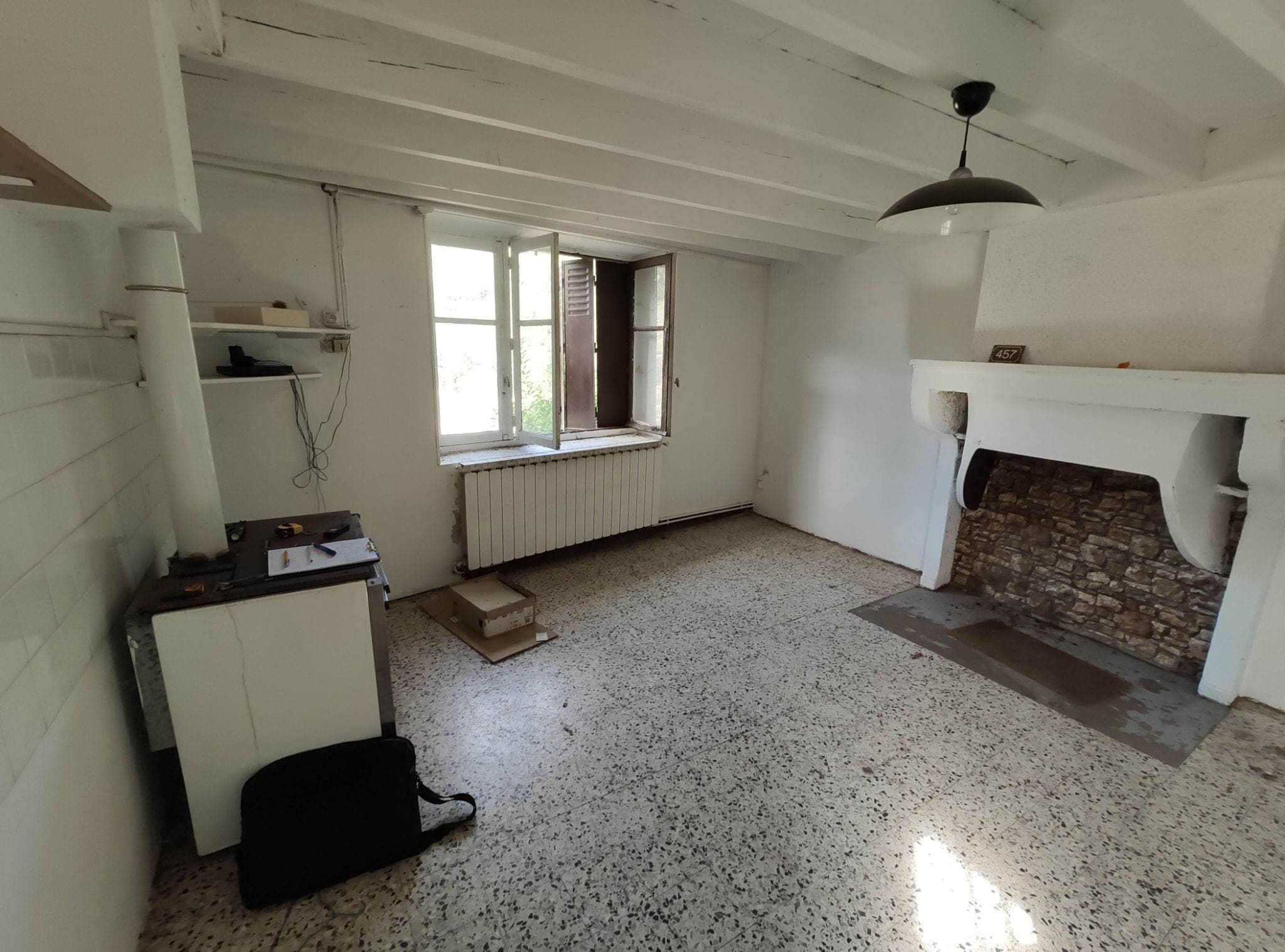 Le même séjour avant travaux : sol en granito, cheminée d’origine et plafond bas