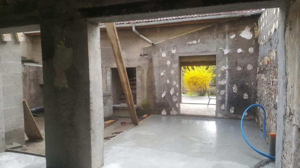 Grange en cours de rénovation : murs en pierre, poteaux et ouverture sur le jardin