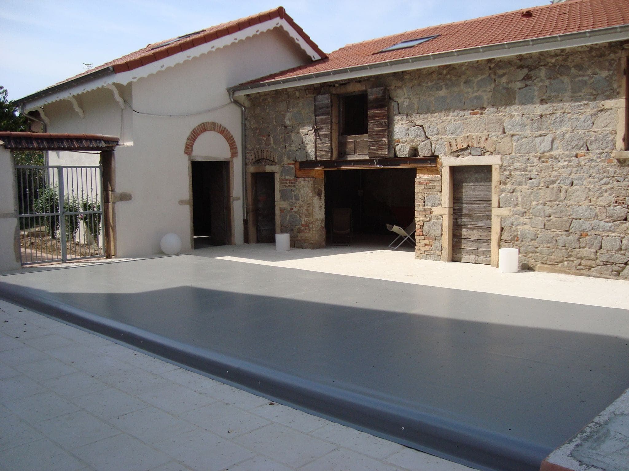 Cour d’une maison en pierre avec piscine couverte