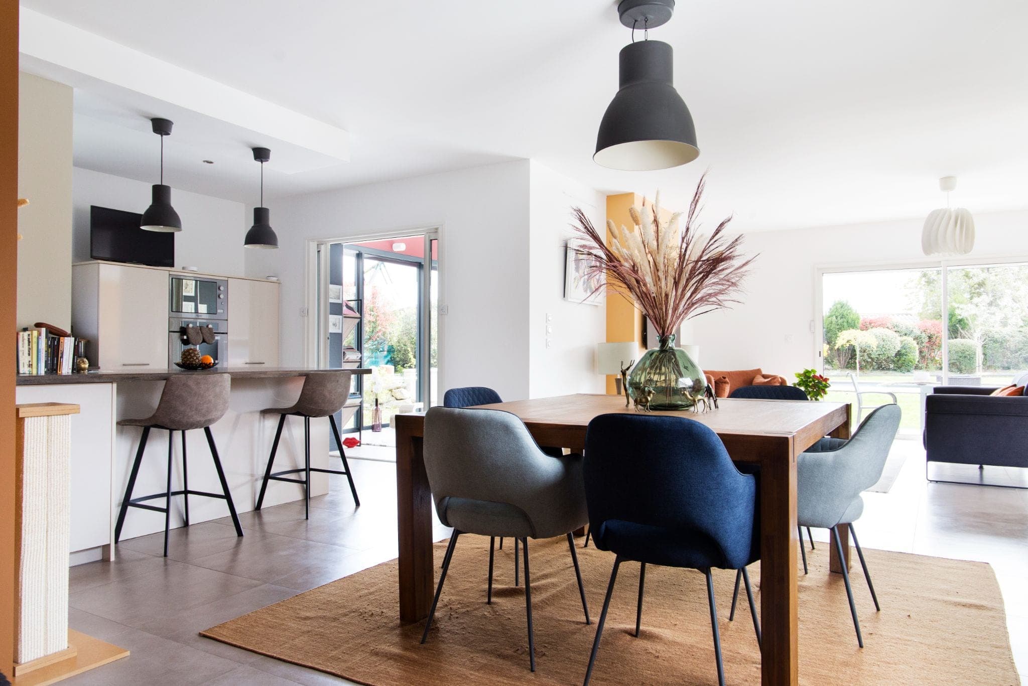 Cuisine ouverte avec bar, table en bois et suspensions noires
