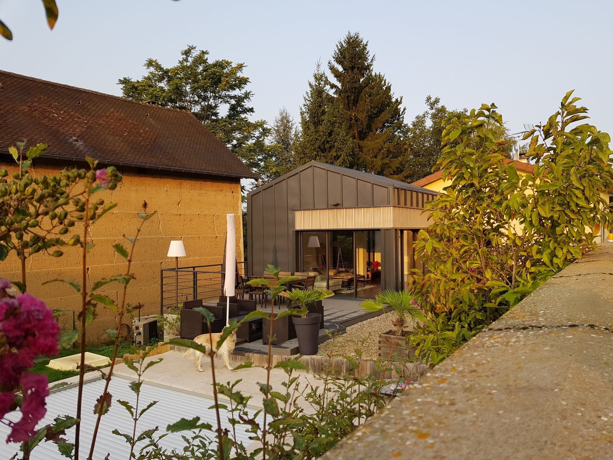 Extension en bardage bois au fond d’un jardin fleuri