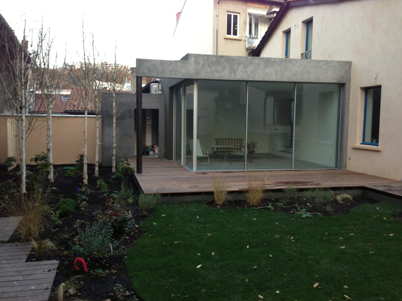 Extension vitrée contemporaine ouvrant sur une terrasse en bois et le jardin