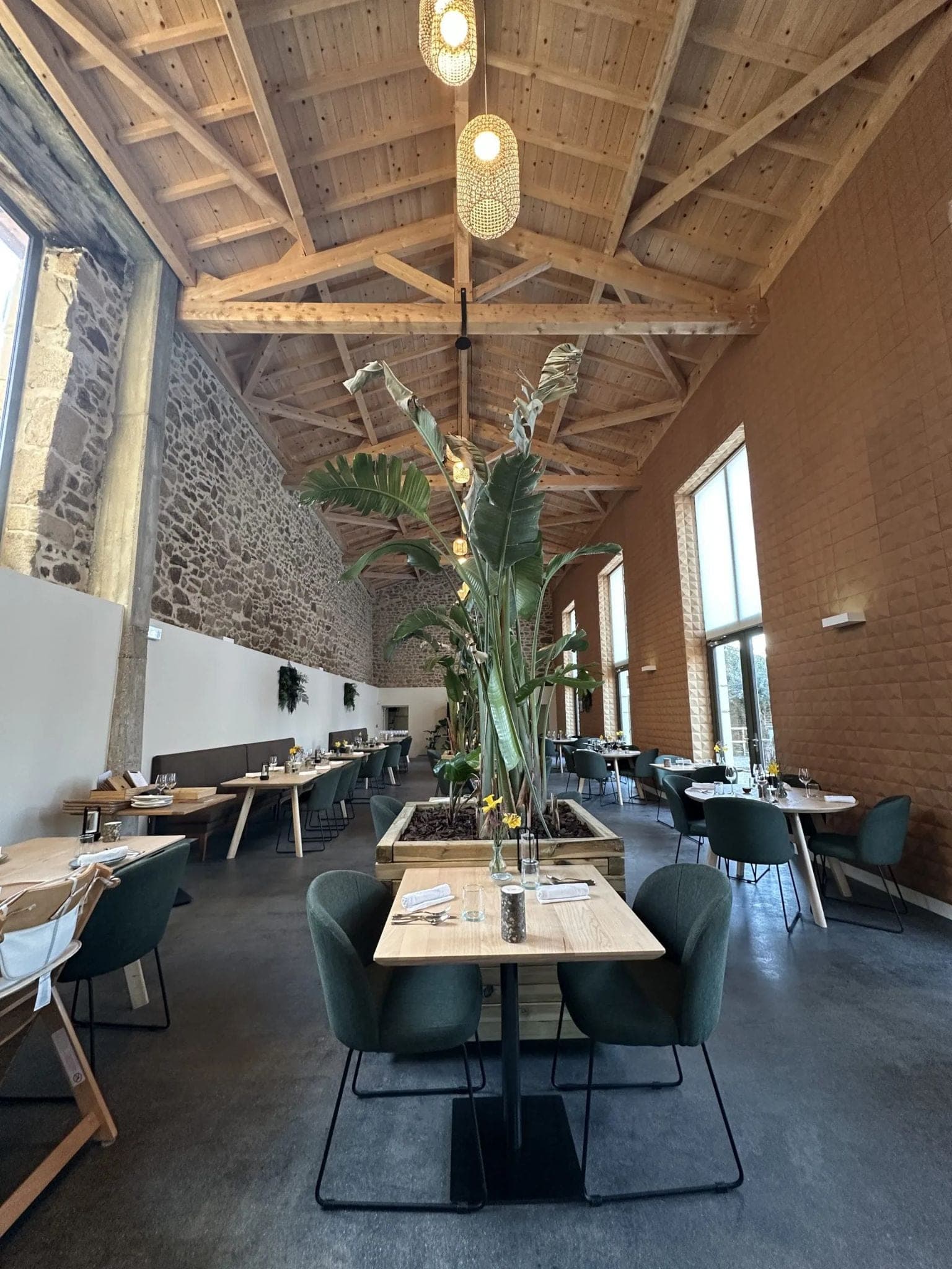 Salle de restaurant dans une grange, charpente bois et mur en pierre