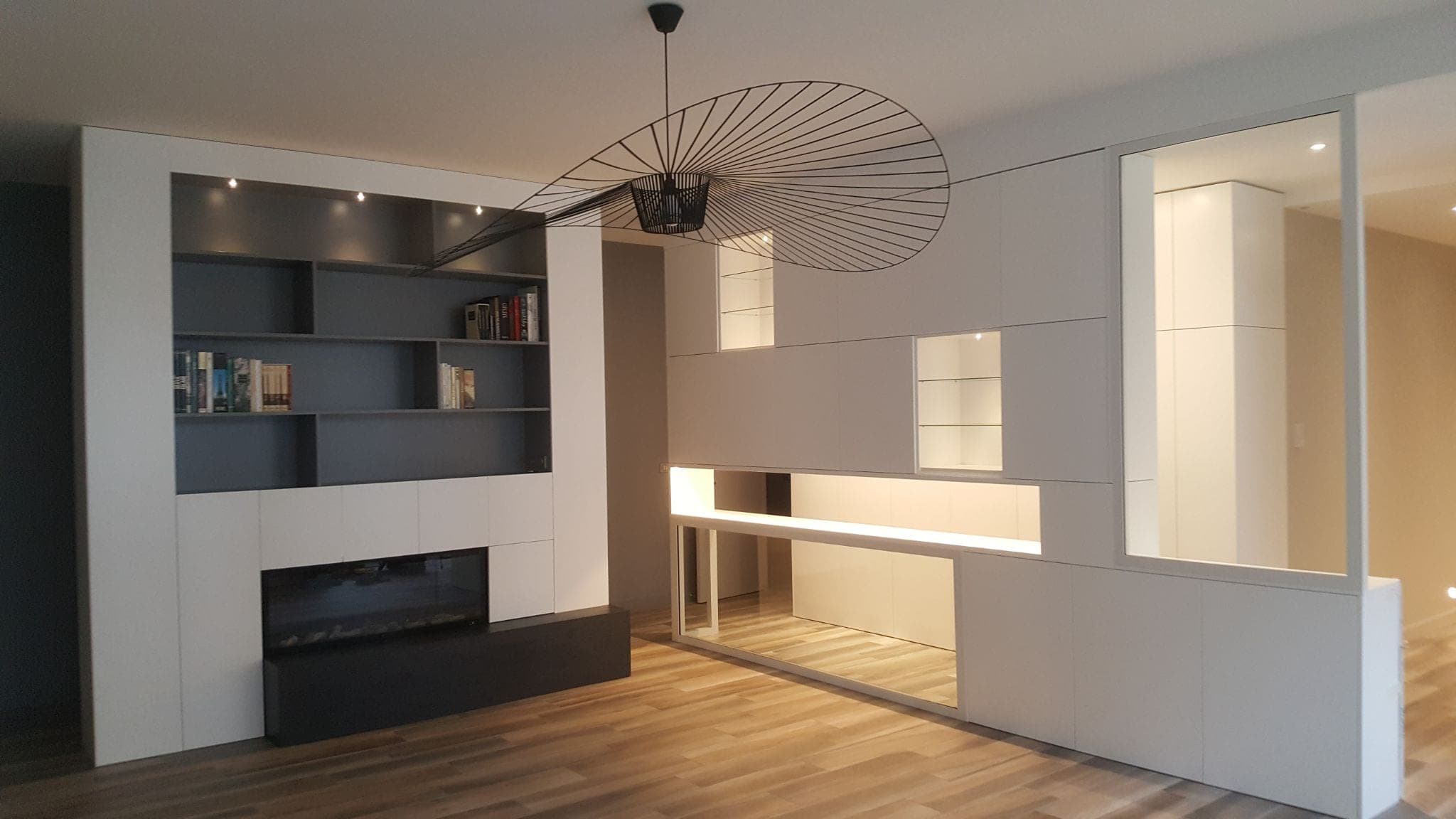 Salon avec bibliothèque sur mesure intégrant une cheminée et des rangements blancs