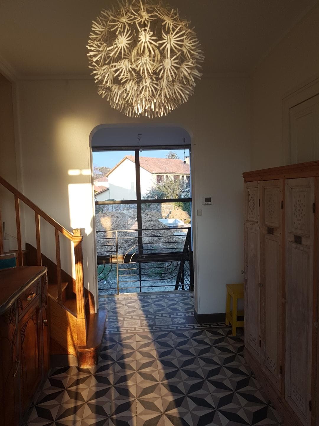Entrée avec carreaux de ciment, escalier en bois et porte vitrée sur la terrasse