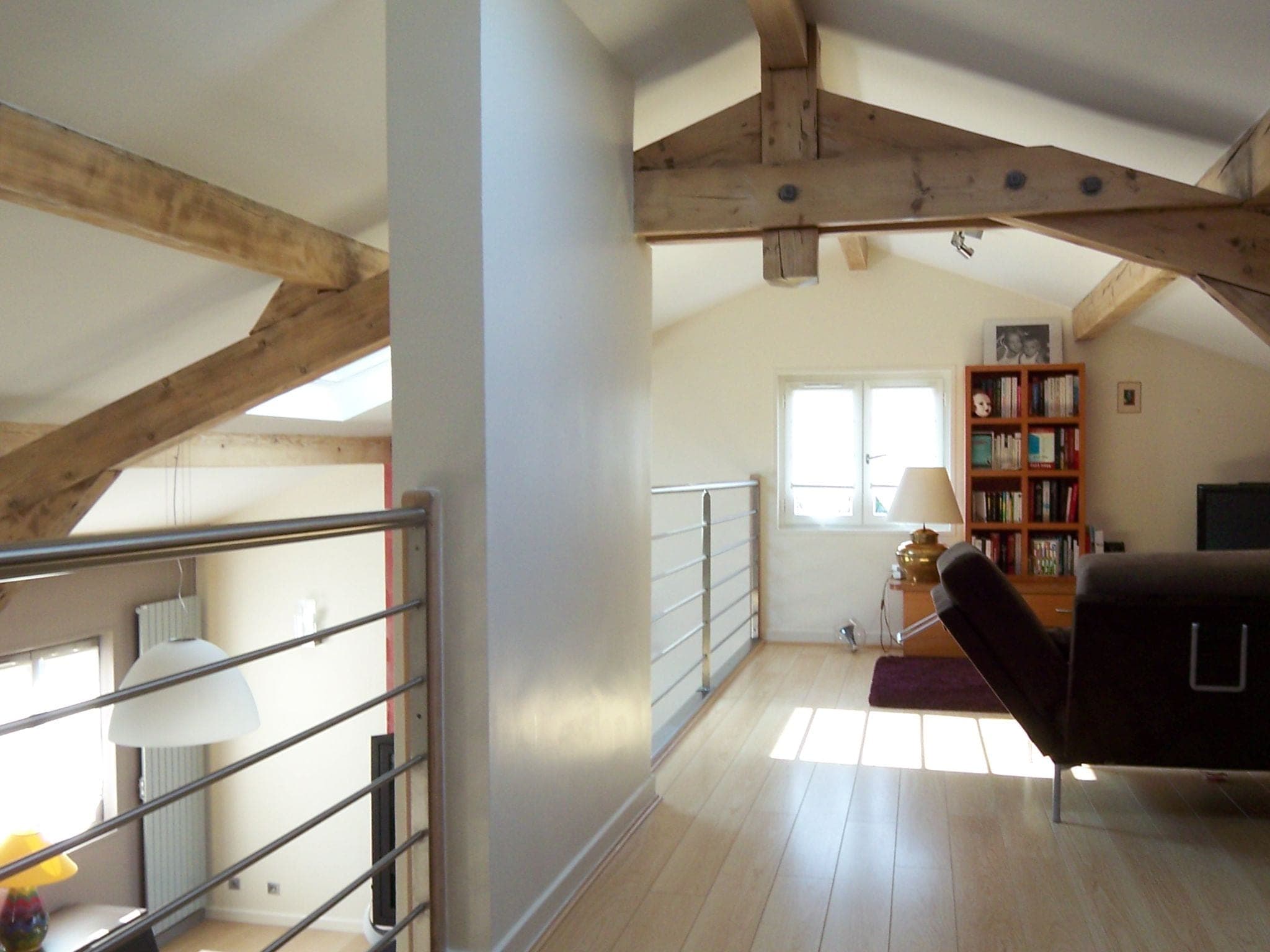 Mezzanine sous charpente apparente avec garde-corps métallique et parquet clair